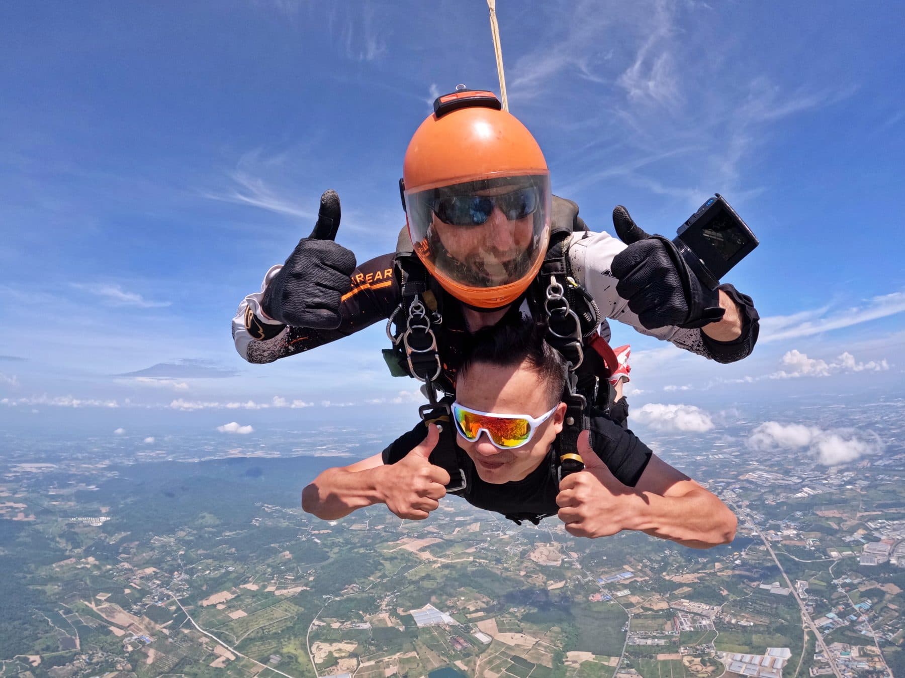 Instructor and passenger giving thumbs up in freefall over the Pattaya countryside