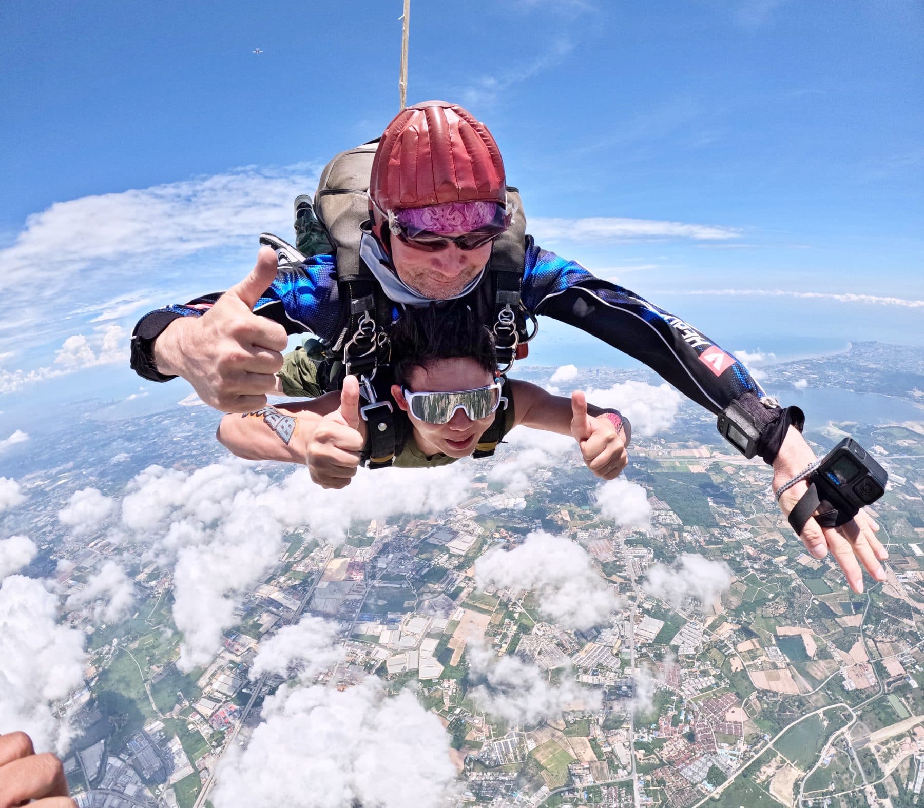 Close-up of a tandem pair in freefall with the coast in the distance
