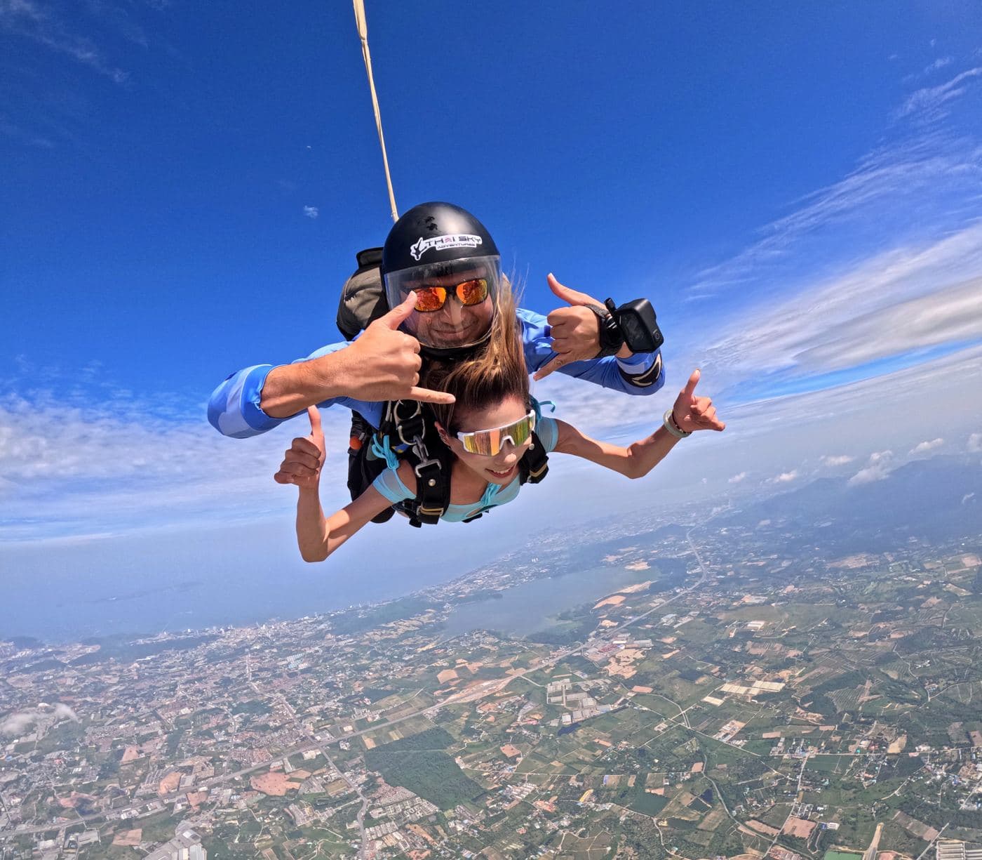 Tandem pair stretching their arms out in freefall under a deep blue sky